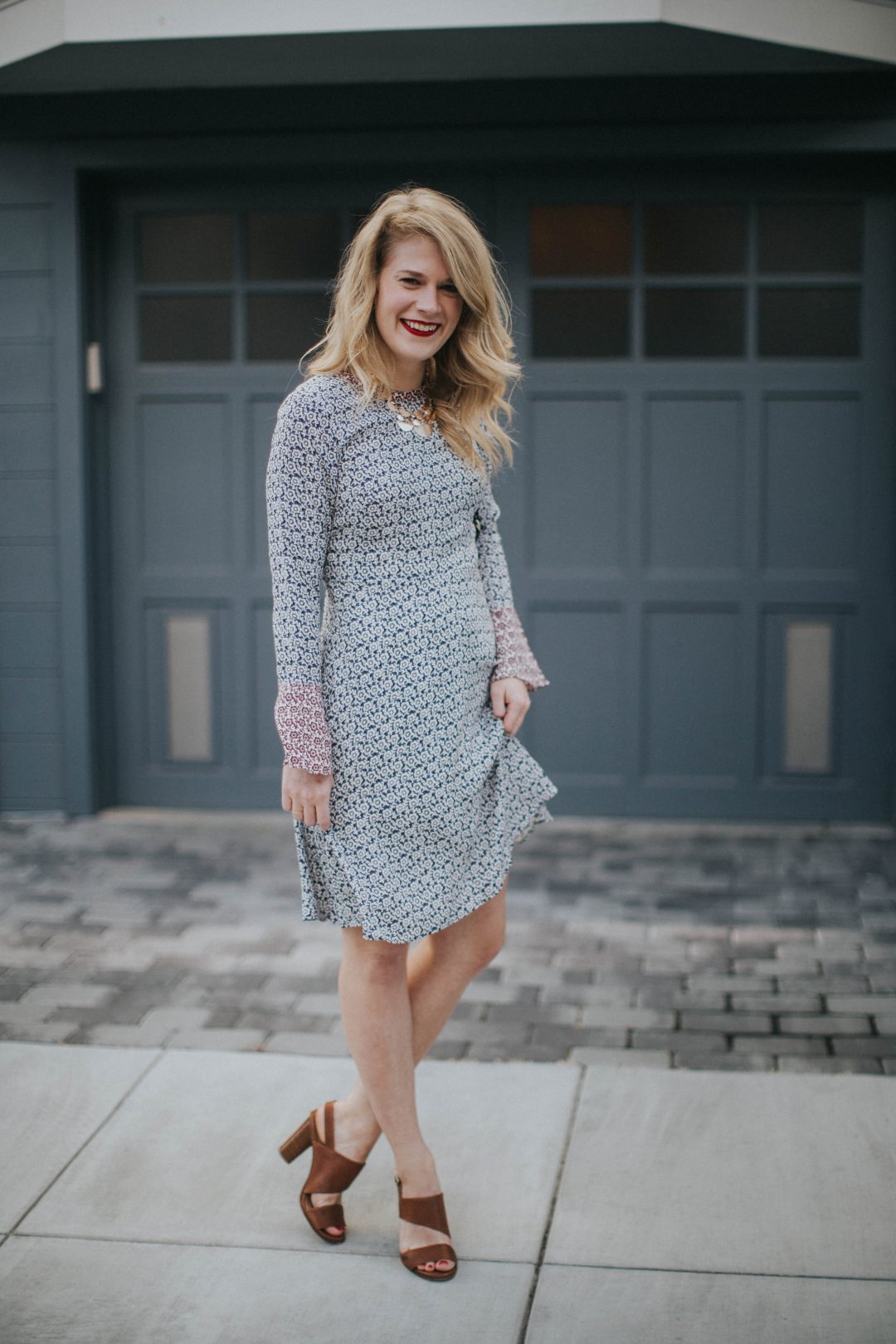 Blogger Cait Weingartner of Pretty & Fun wearing a LOFT floral bell sleeve dress with M. Gemi sandals and a BaubleBar statement necklace.